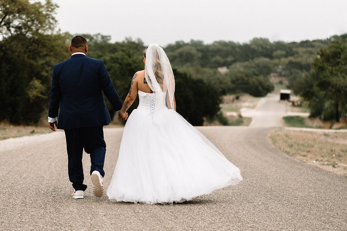 bride and groom walking down street holding hands at canyon lake cabins.