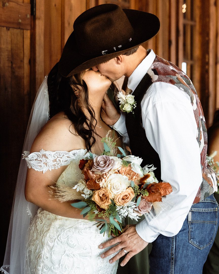 cowboy groom kissing bride after wedding ceremony at Texas Old Town - Sage Hall