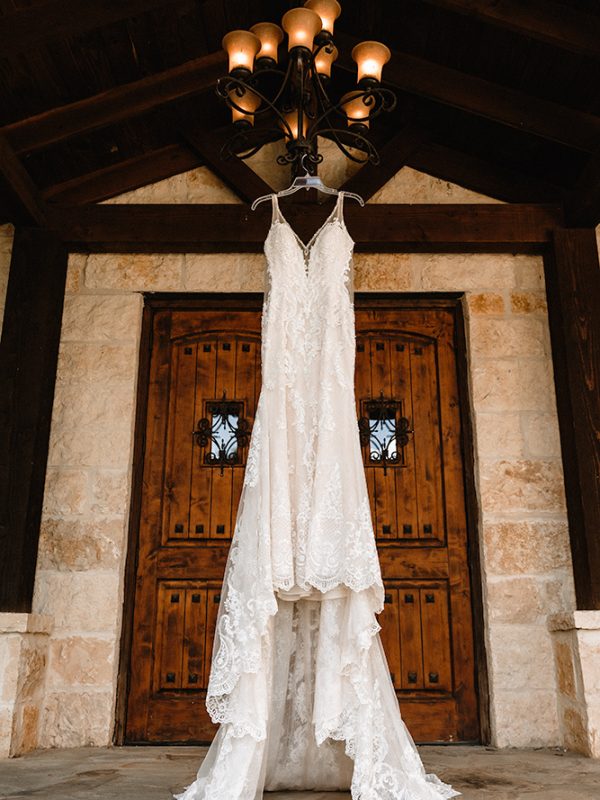 Photo of bride dress hanging on chandelier at The Marquardt Ranch wedding venue in Boerne, TX
